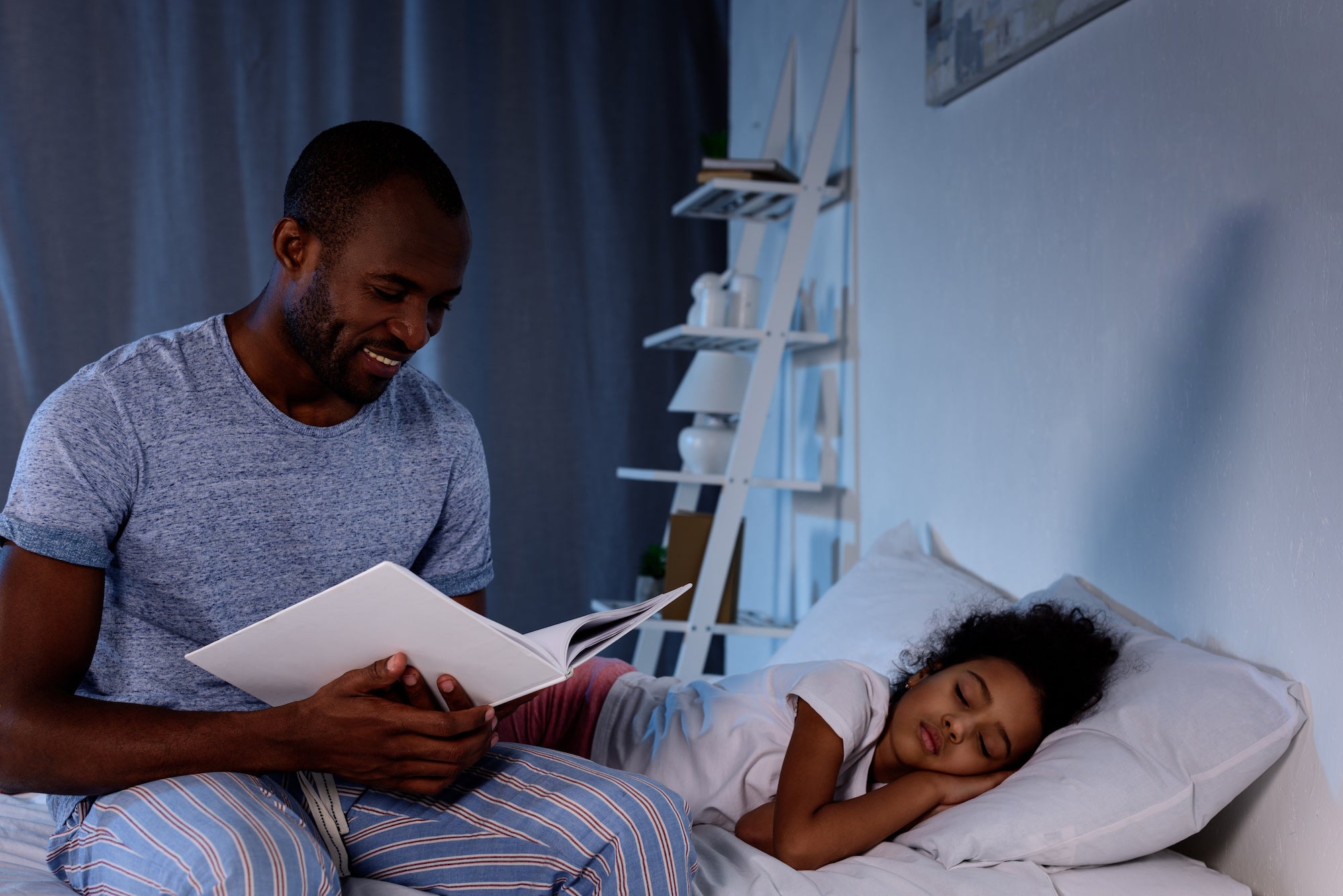 a dad reading to his kid as she falls asleep following a bedtime routine that helps kids sleep.